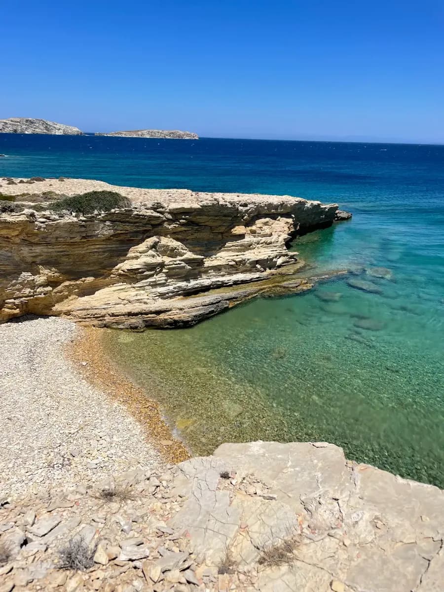 A clear-water rocky cove on Lipsi beneath a blue summer sky